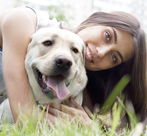 woman smiling with dog in grass